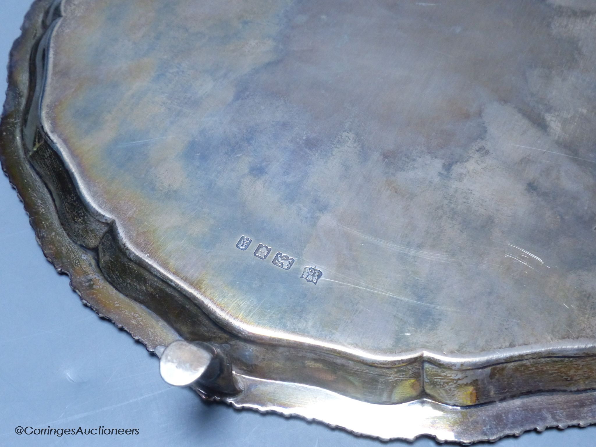 A circular silver salver with shaped gadrooned edge, on three hoof feet, 14.79oz
